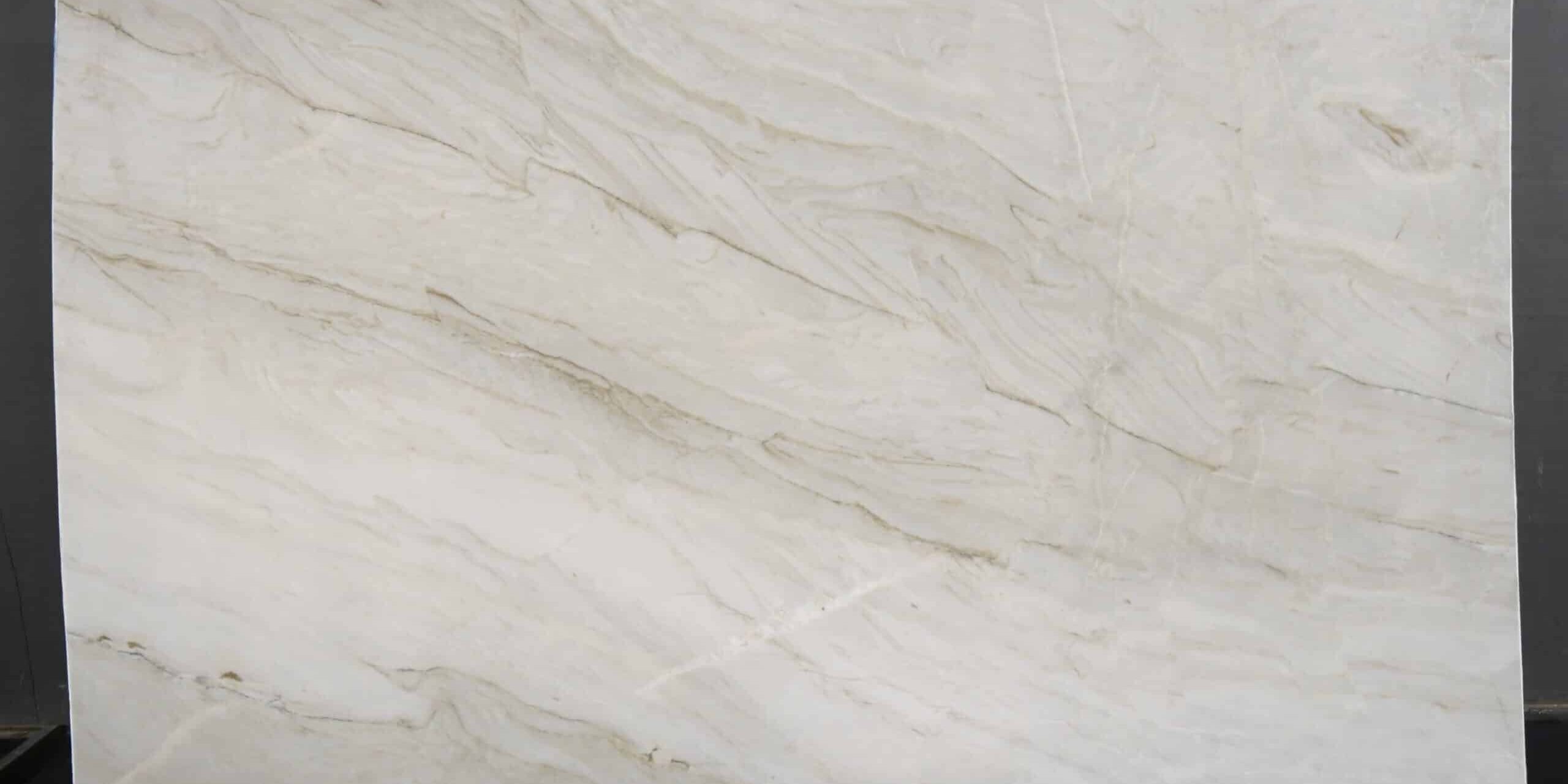 Full view of a White Taj Quartzite slab showcasing its luminous ivory background and gentle, sweeping gold and taupe waves.