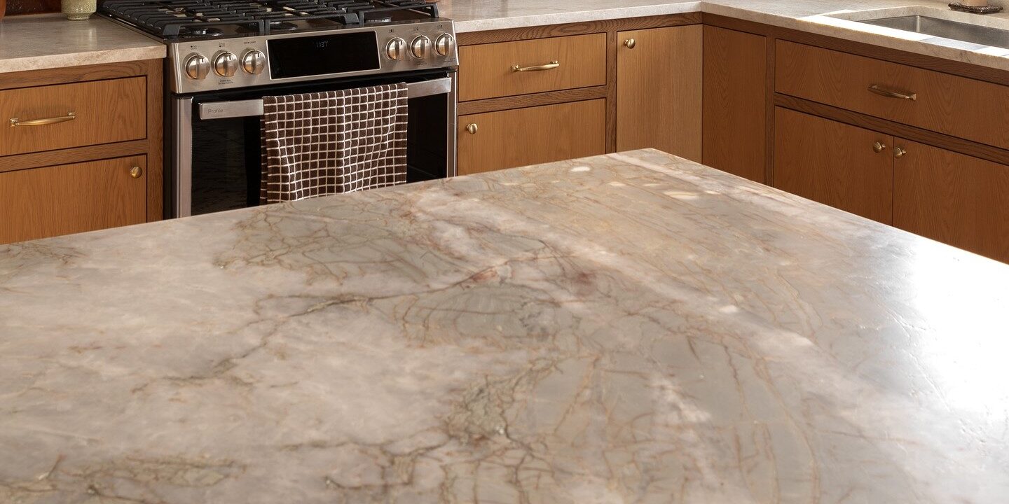Kitchen island featuring white and gold quartzite surfaces with wooden cabinetry.