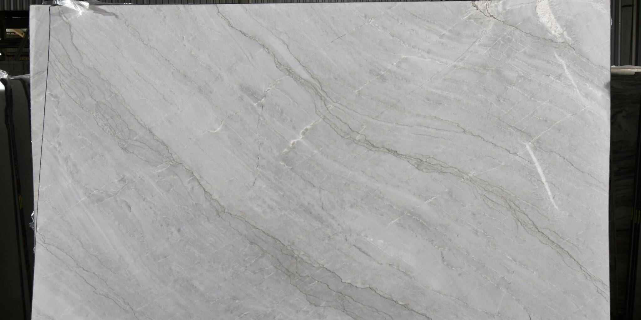 Large format white natural stone slab with soft grey movement, ideal for book-matching.