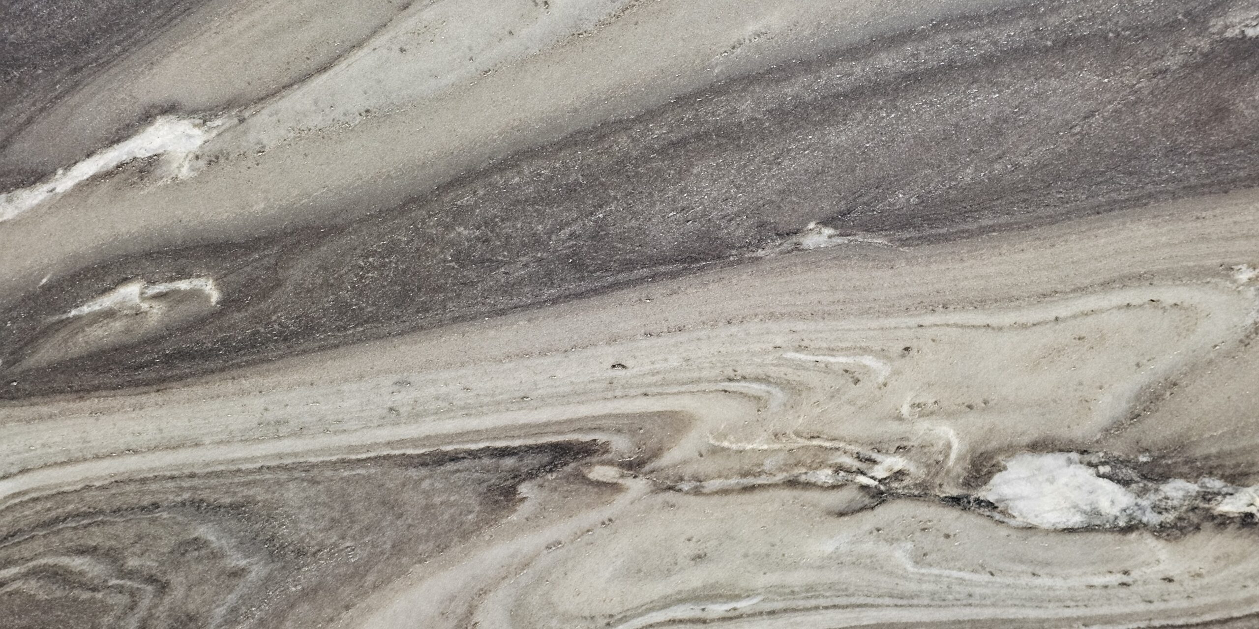 Detailed view of the dark charcoal and smoky grey wave patterns in a Bali Quartzite slab.