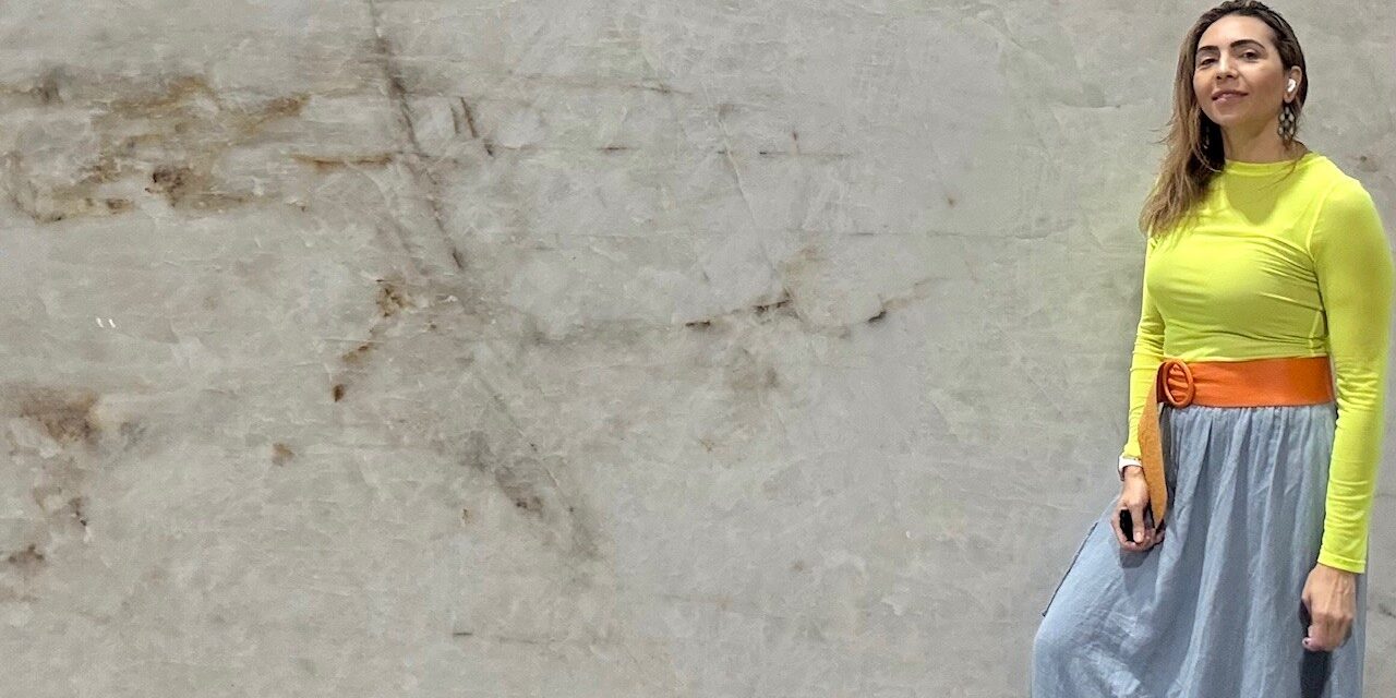 Unique Stone Boutique founder presenting a hand-selected block of luxury quartzite in the showroom.