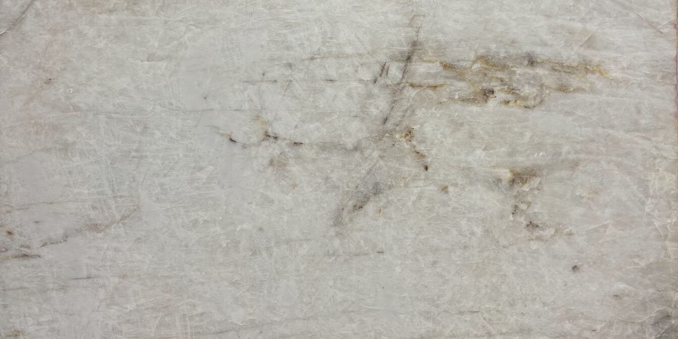Full slab of premium white quartzite showing natural golden-brown veins and polished finish.