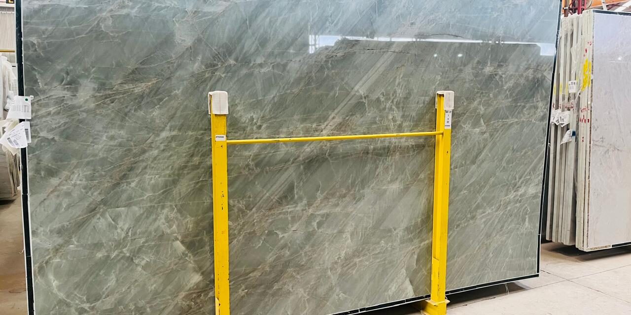 Full view of a polished emerald quartzite slab in a warehouse setting.