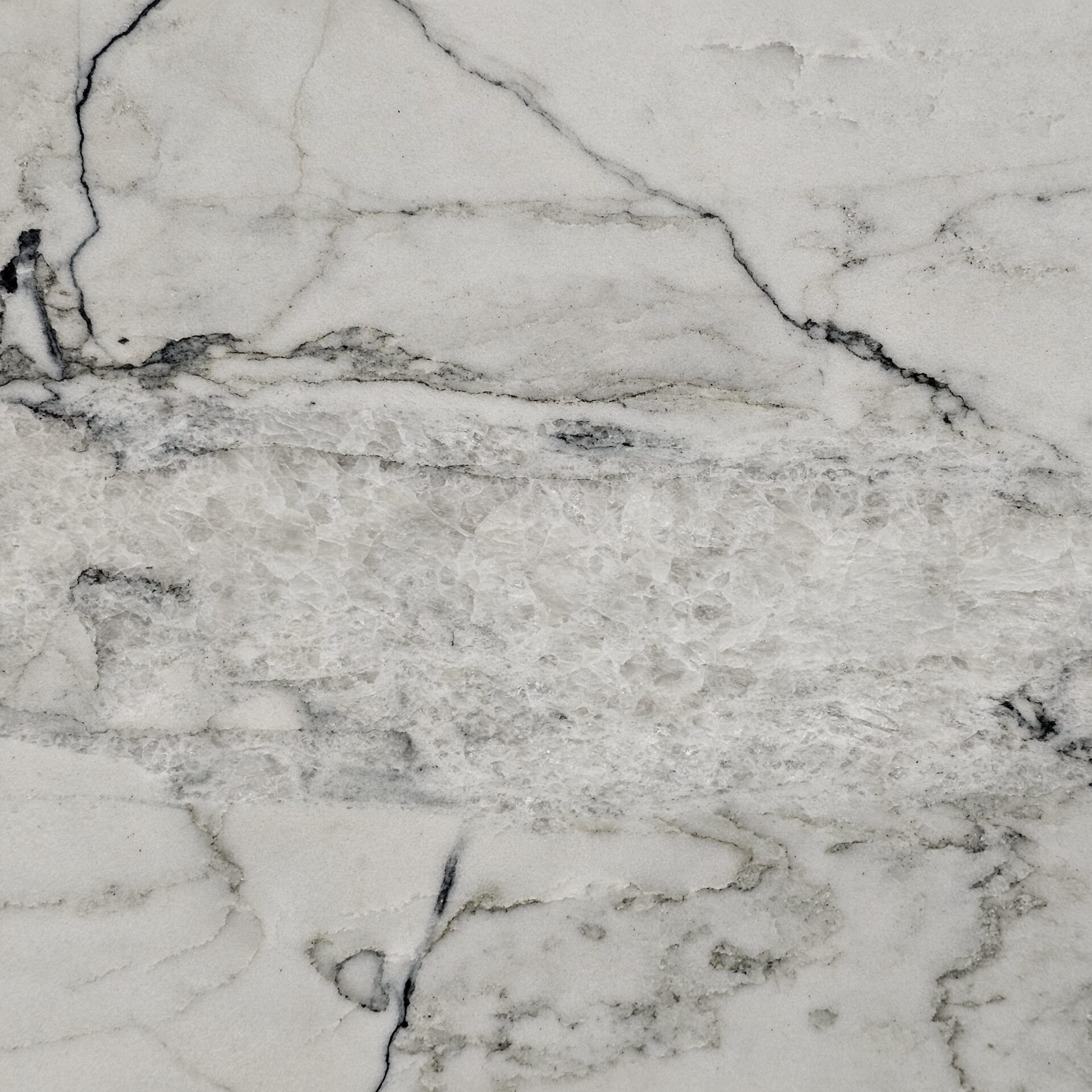 Detailed view of the sharp charcoal fractures and white crystalline background of Fantasy Lux Quartzite.
