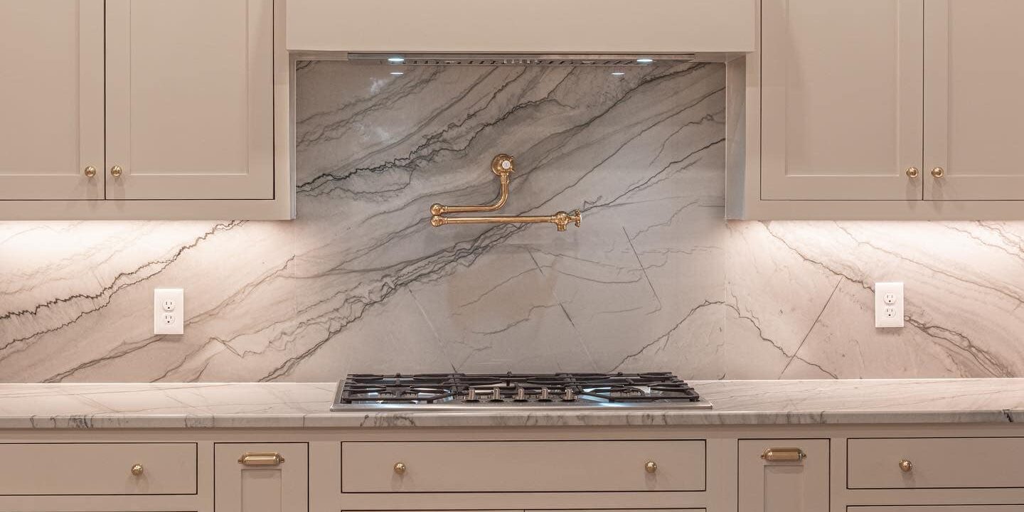 Bright and airy kitchen featuring an expansive island made of durable white natural stone.