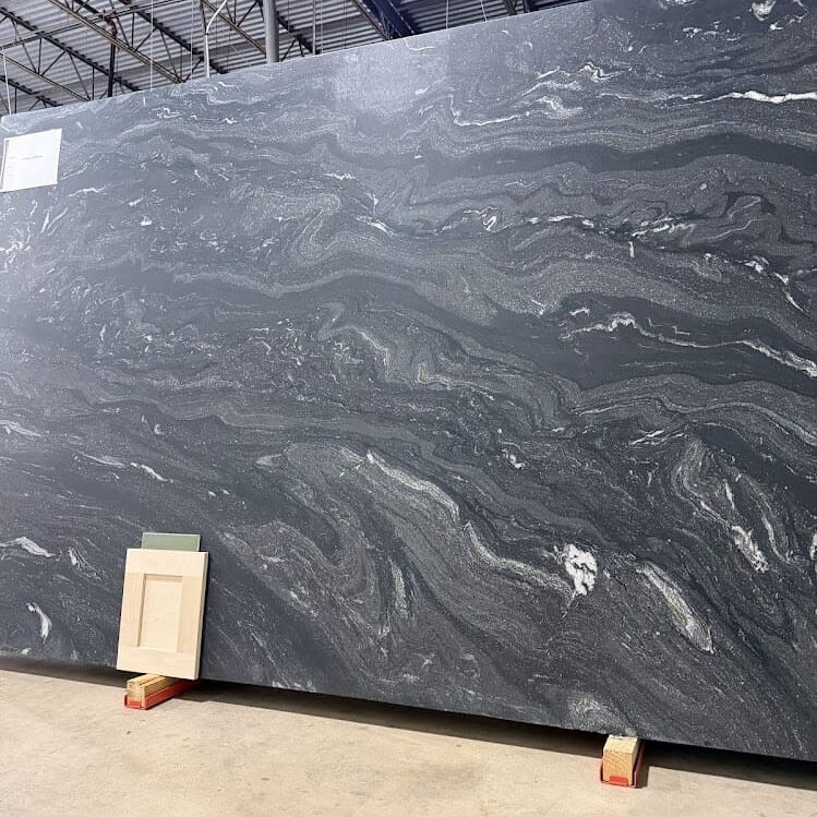 Full portrait of an authentic dark granite sheet inside a warehouse, highlighting its soft, non-reflective finish.