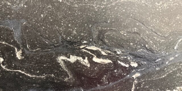 A close-up view of Makalu granite showcasing the fine white crystalline flecks embedded inside its textured charcoal-black surface.