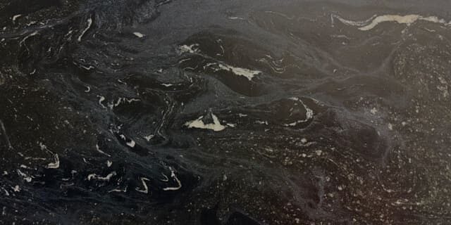 Close-up of a matte dark stone edge showing the uniform mineral structure and low-contrast details.