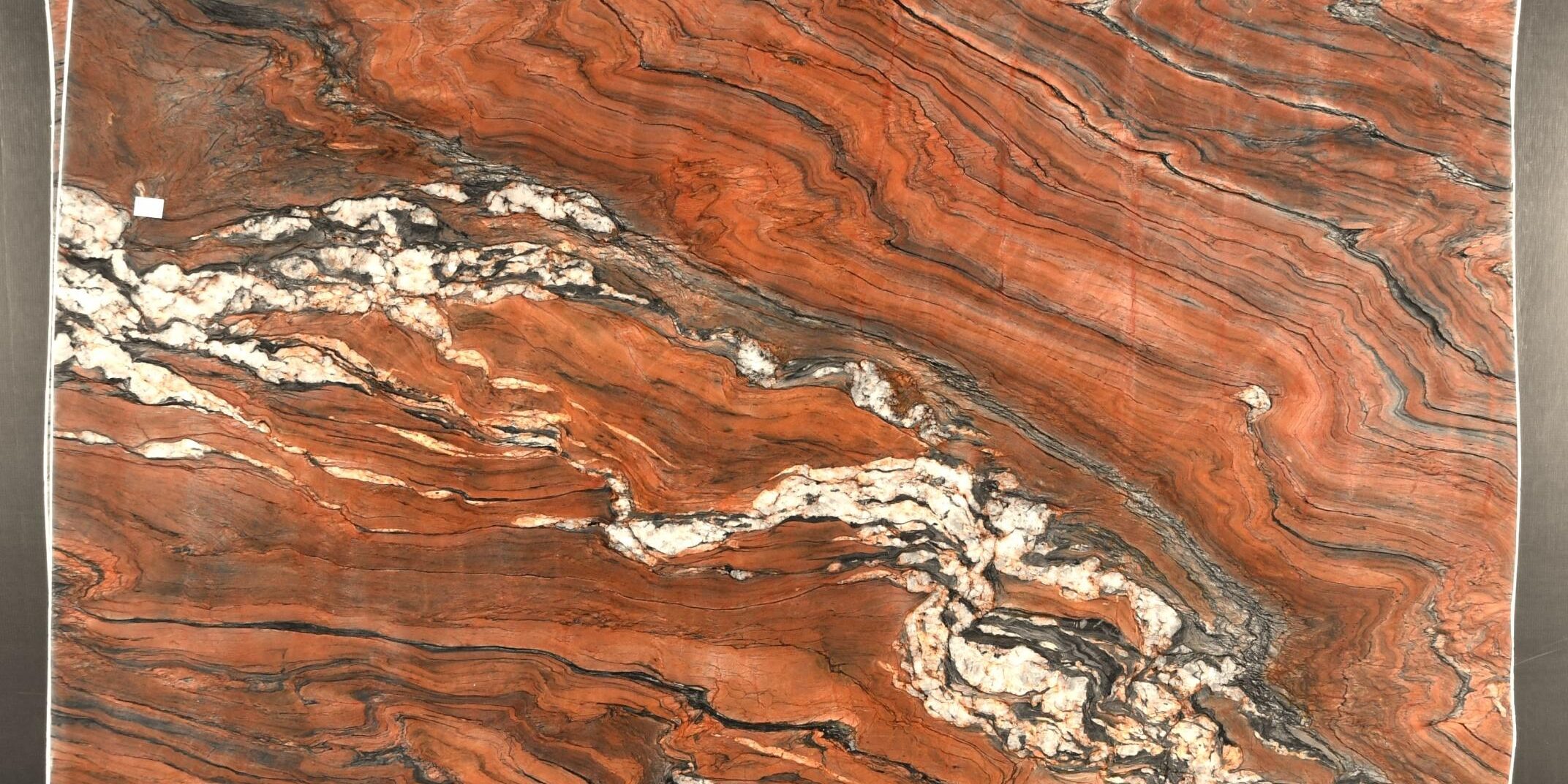Full slab view of red quartzite featuring a dramatic, swirling storm-like pattern.