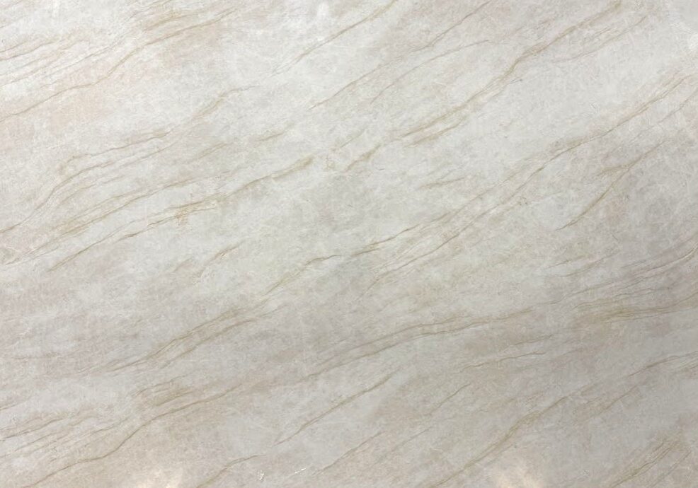 A full-view display of a Taj Mahal Quartz slab featuring a creamy almond background and sweeping diagonal gold veining.