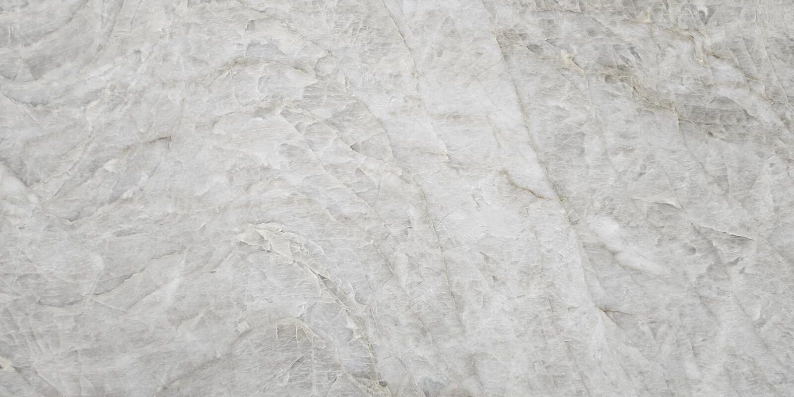 Macro view of the creamy beige crystalline texture of a honed stone surface.