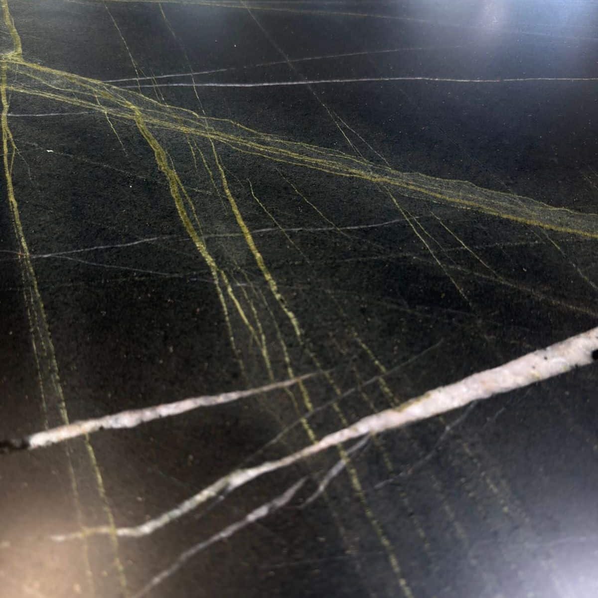 Close-up detail of the vibrant green and white veins cutting through the deep black Tellus Quartzite.