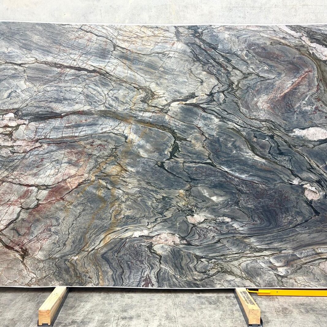 Full display of a premium Tempest Blue Quartzite slab showcasing its sweeping diagonal movement of blues, grays, and copper tones.