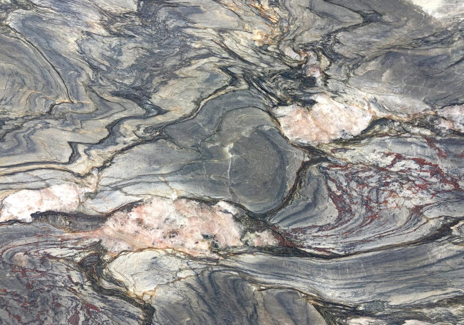 A close-up shot capturing the sharp contrast between dark charcoal gray waves and a sudden, thick white quartz vein.