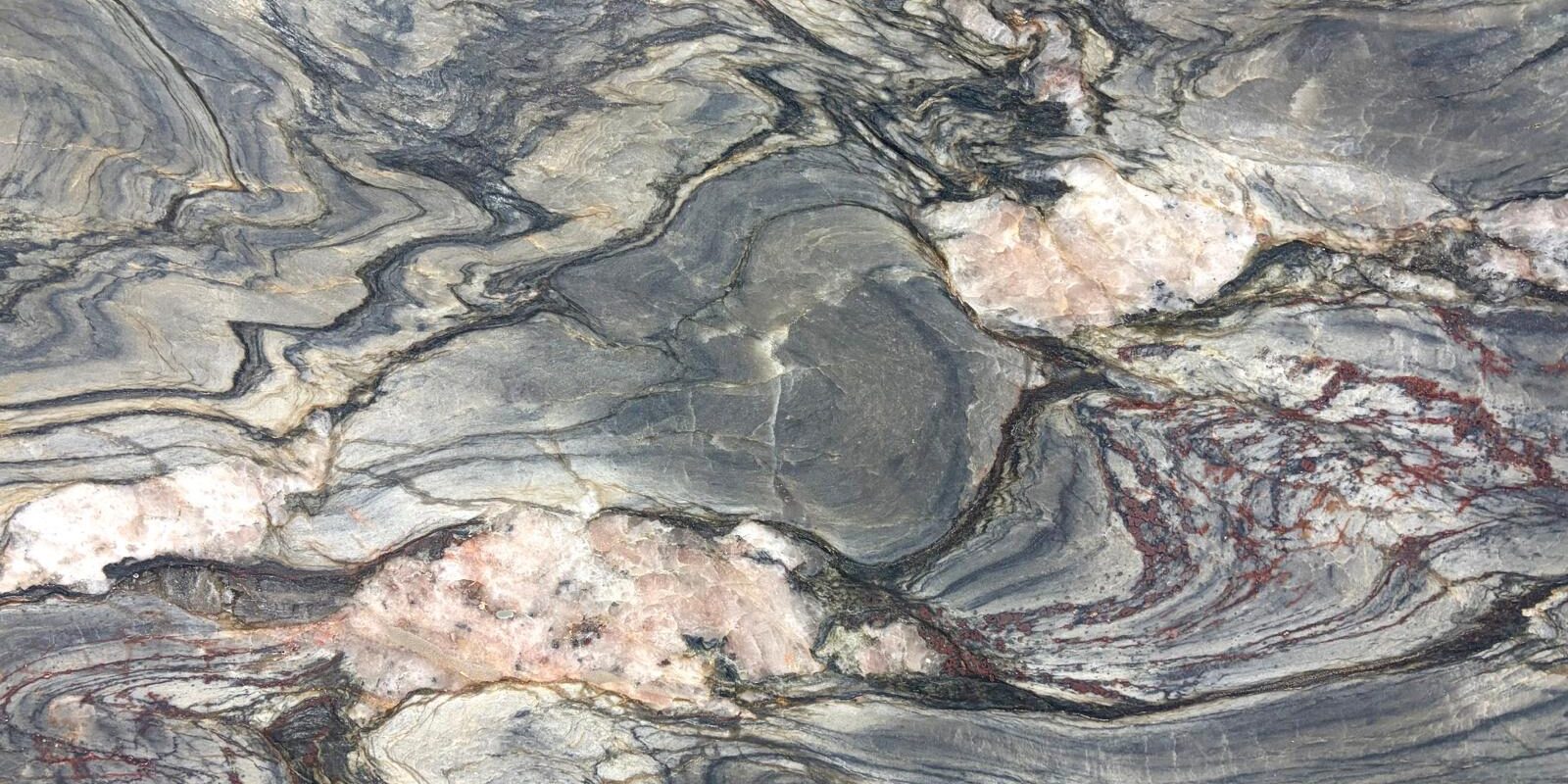 A close-up shot capturing the sharp contrast between dark charcoal gray waves and a sudden, thick white quartz vein.