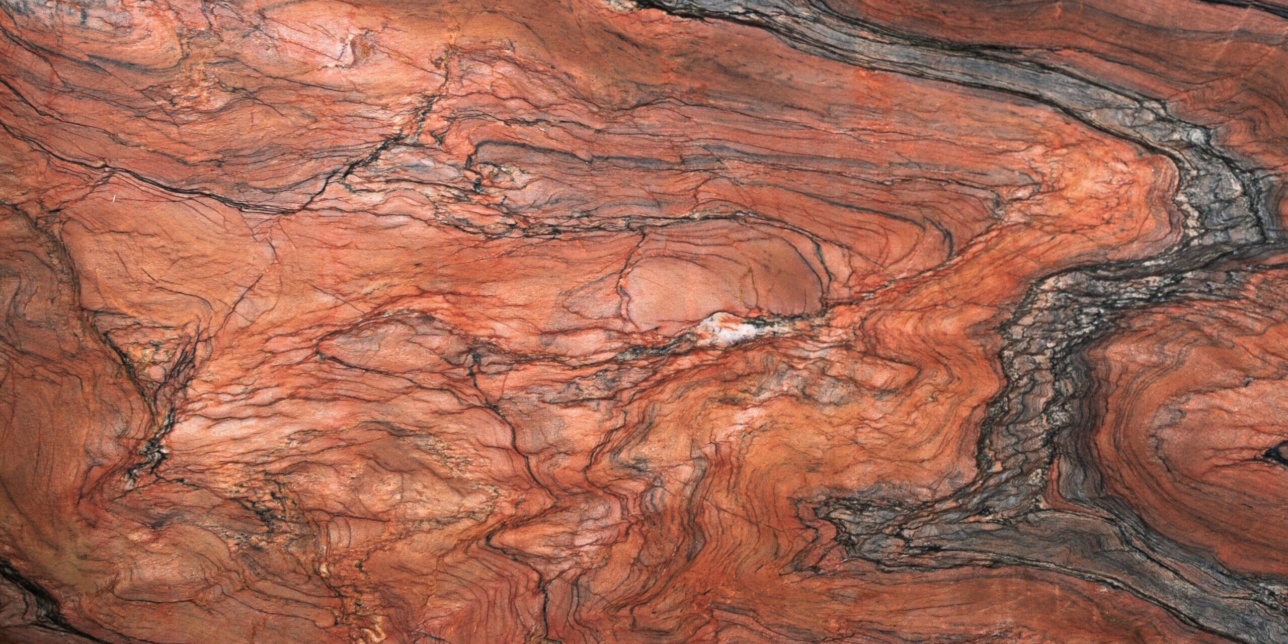 Detailed texture of Tempest Red stone with high-contrast charcoal veining and earthy orange tones.