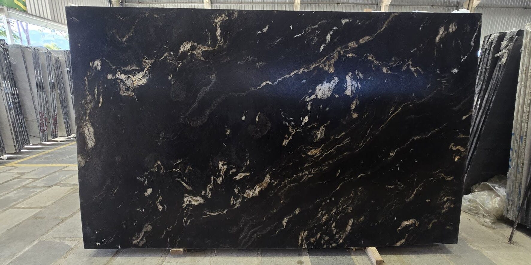 Full view of a polished Titanium Gold Granite slab showcasing its sweeping cosmic pattern and dramatic diagonal gold bands.