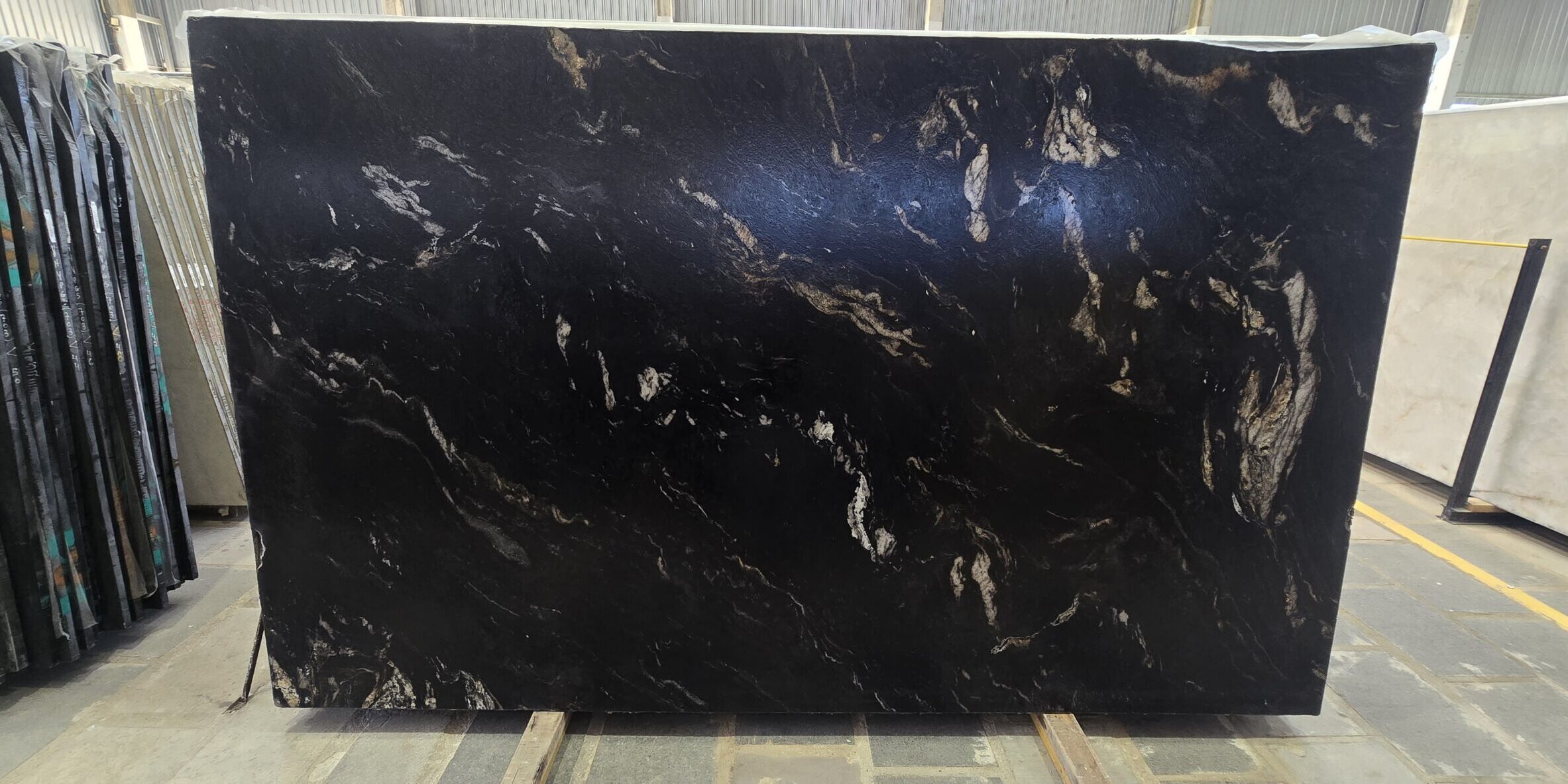 A large-scale display of an authentic dark granite block showing excellent consistency in its volcanic gold vein structure from edge to edge.