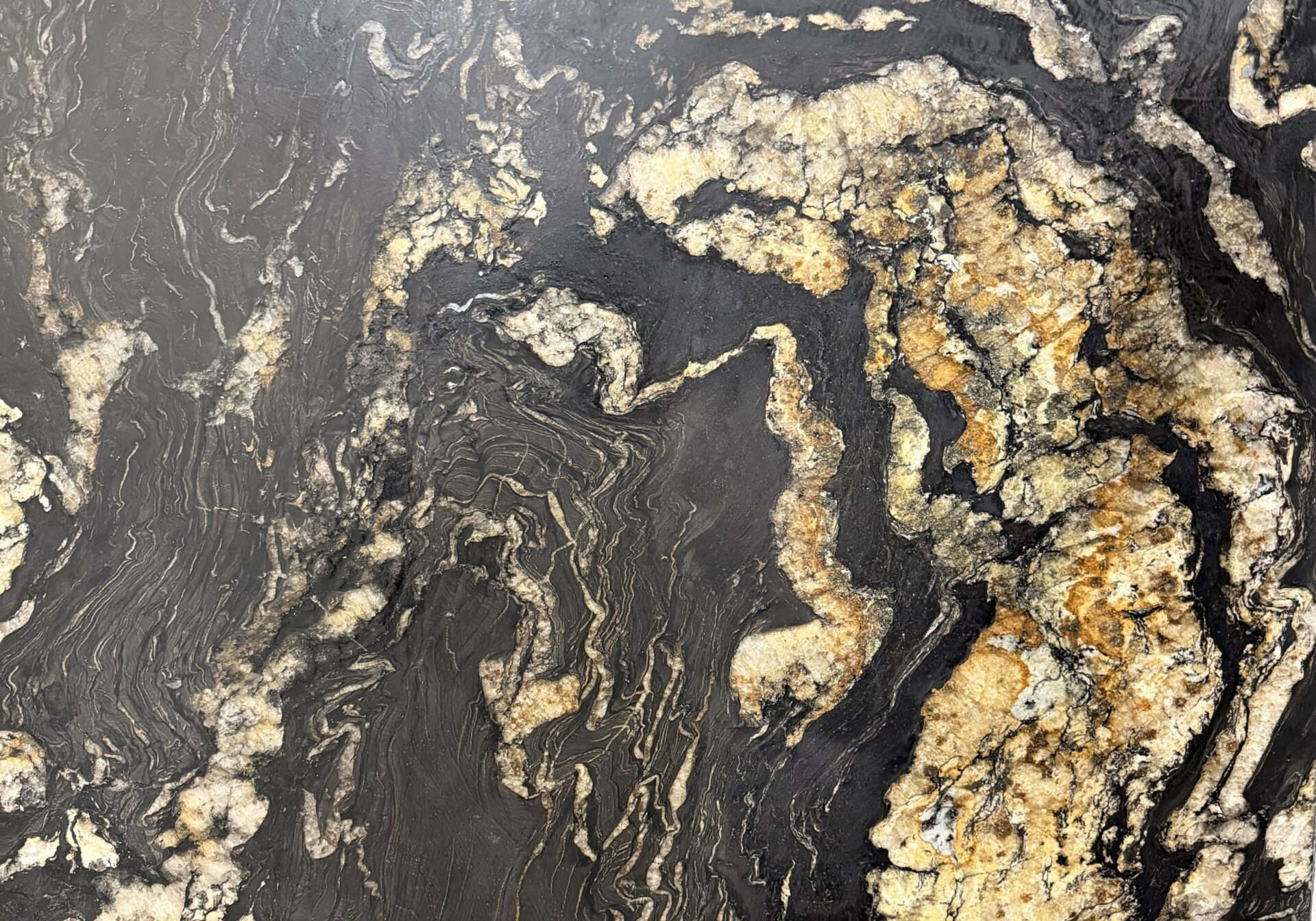 A close-up view of Titanium Gold Granite showing the high-contrast detail of its deep black background and shimmering golden mineral swirls.