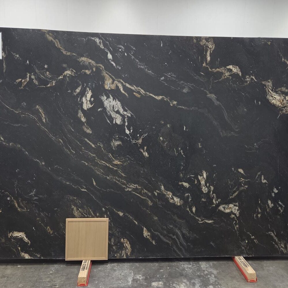 A full Titanium Gold Granite slab displayed right behind a light, clean white oak wood cabinet door mockup to showcase material coordination.