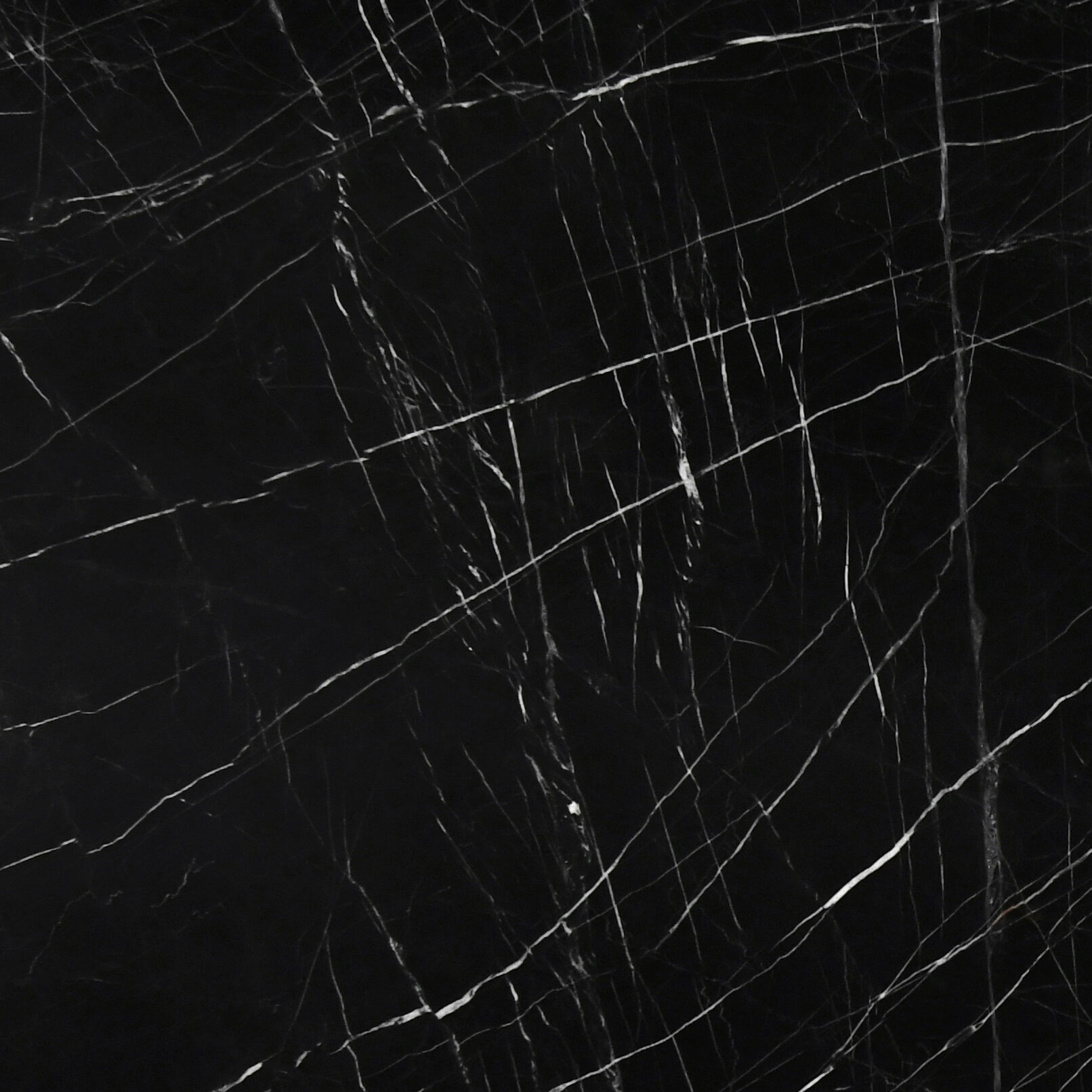 Macro shot of the high-gloss finish on an obsidian black natural stone with fine white fractures.