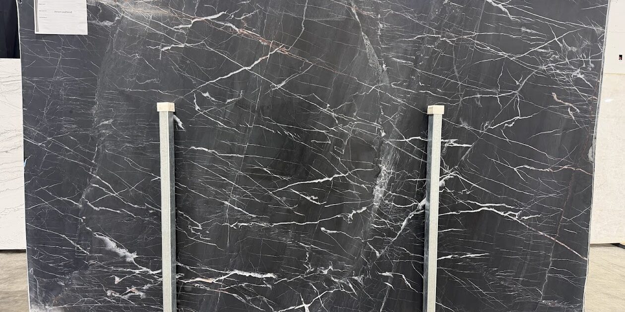 A full-format natural stone slab with a leathered finish, highlighting the dramatic contrast of a pure black background and electric white lines.