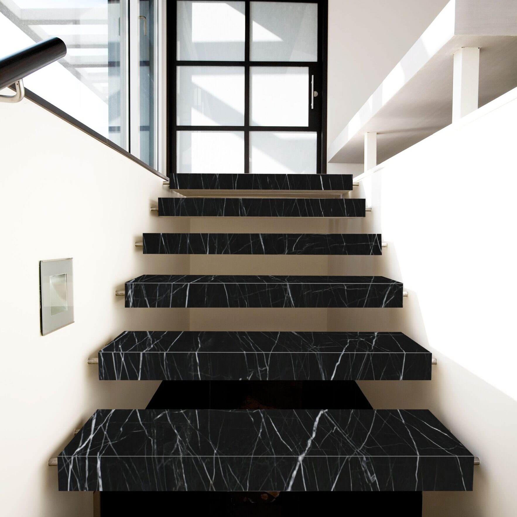 Elegant interior staircase with solid black stone treads and striking white linear movement.