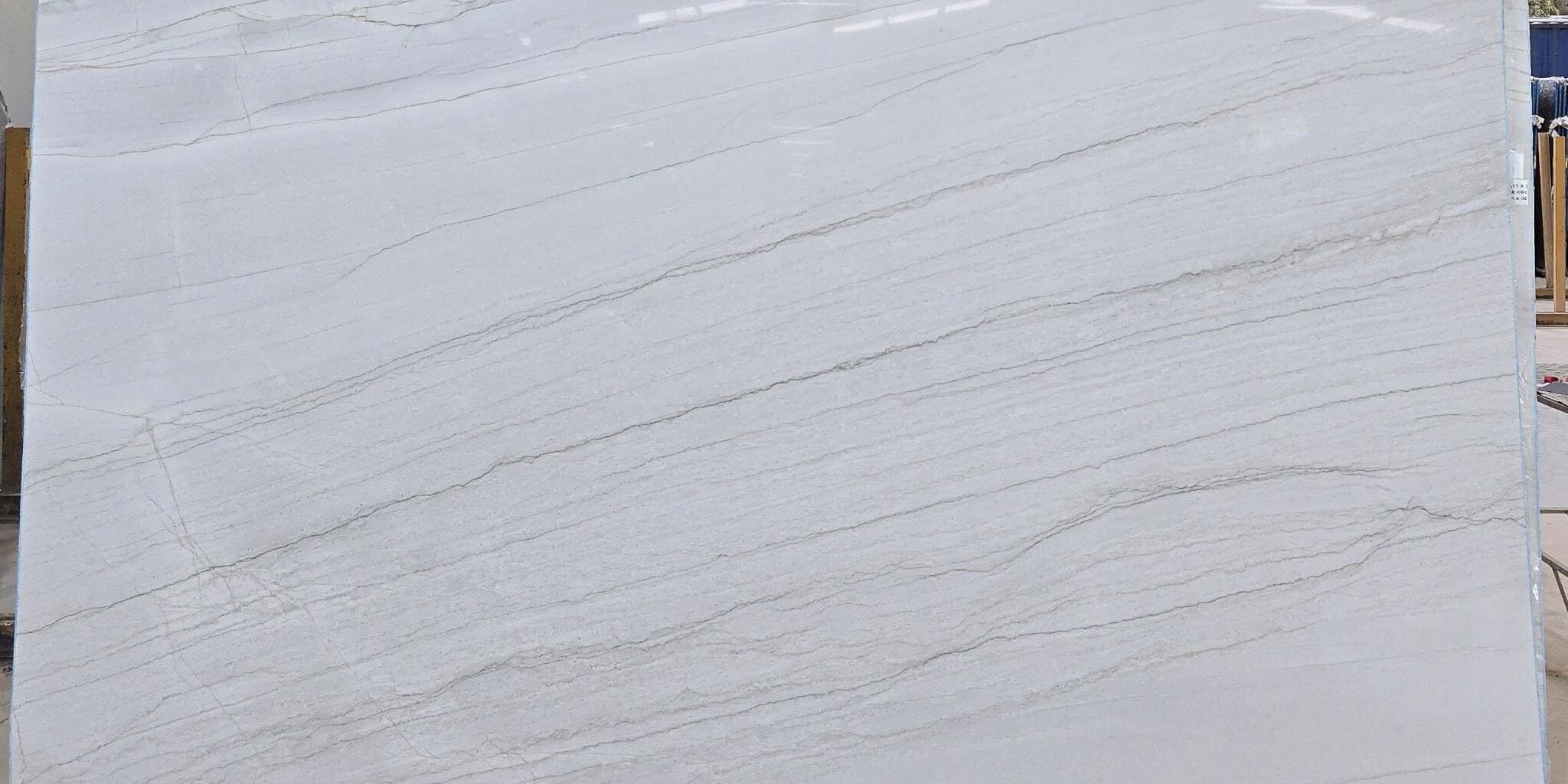A large-scale display of an open-faced white quartzite bundle with soft ash-gray and greige lines.
