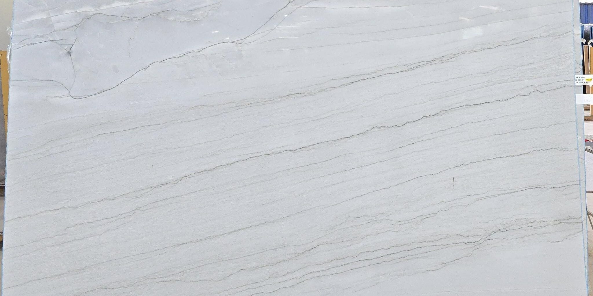 A polished white natural stone slab showcasing a balanced, low-contrast pattern ideal for seamless book-matching.