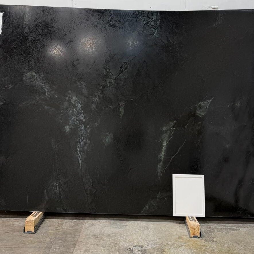 Full slab of Black Soapstone featuring a deep charcoal gray background with dramatic veining, organic movement, and subtle light mineral streaks across the surface.