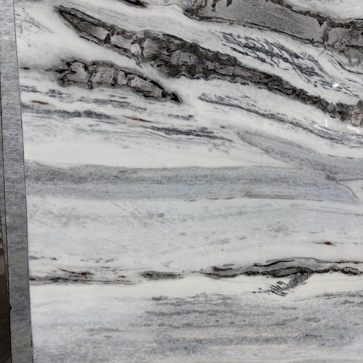 A detailed macro view of natural stone showcasing the crystalline intersection of an icy white background and a dense gray mineral band.