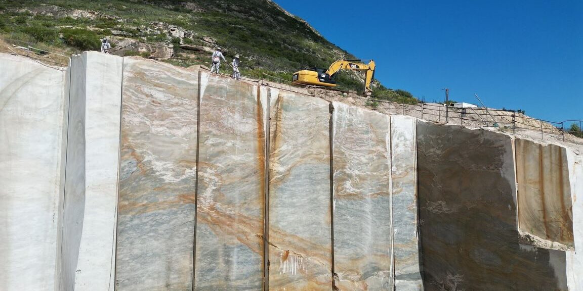 Raw block of premium quartzite being inspected at the quarry for quality and color consistency.