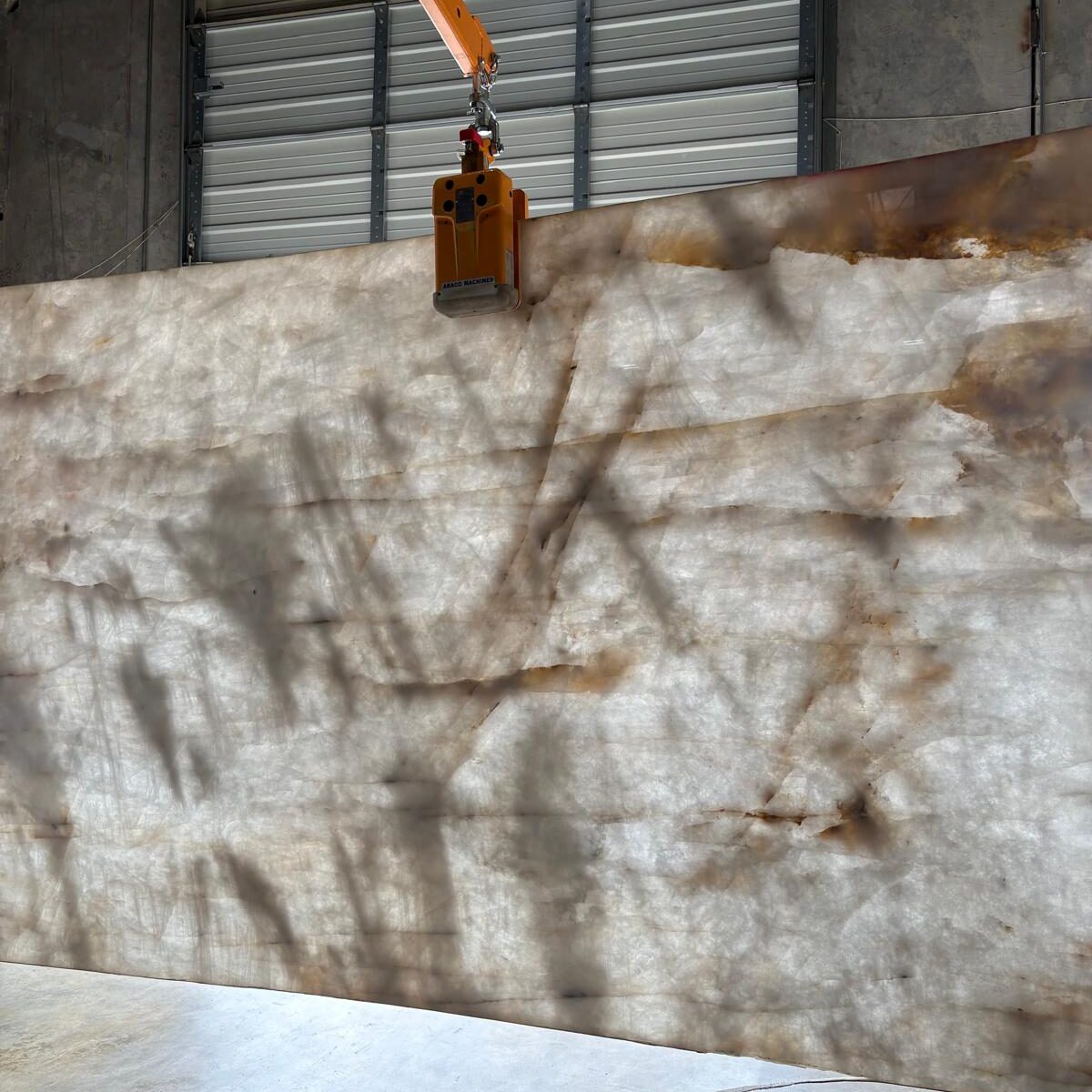 Full view of a cristallo gold quartzite slab showcasing its luminous white background and elegant movement.
