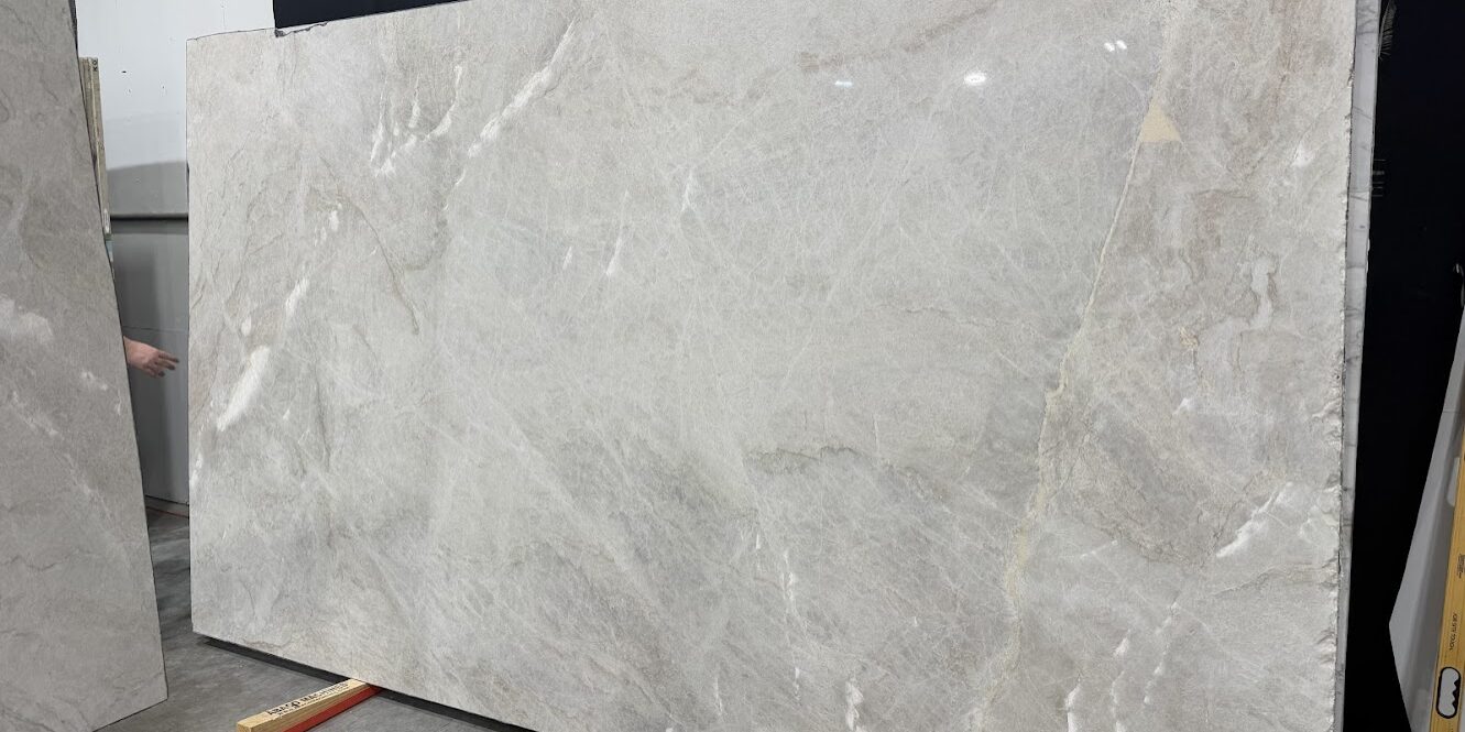 A large-format Brazilian quartzite slab displaying a balanced, light-reflective surface with soft gold and sandy highlights.