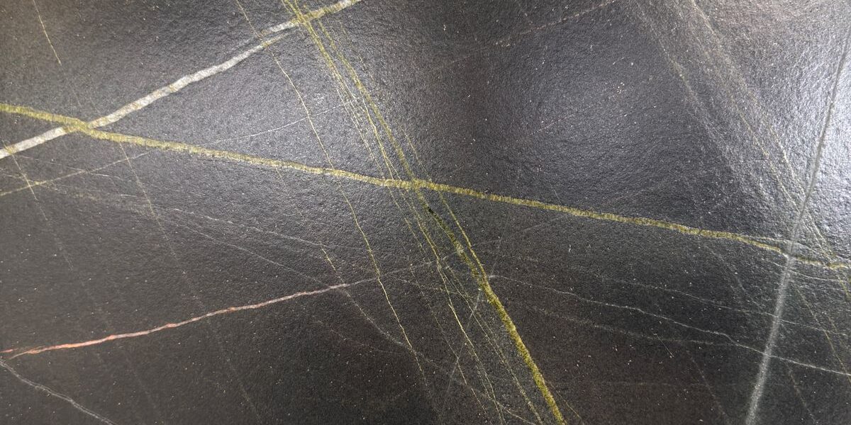 Macro view of the unique mineral structure and saturated dark tones of a premium natural stone.