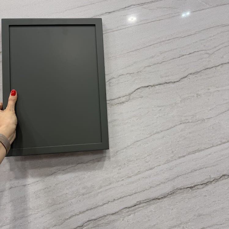 A close-up view of White Santorini Quartzite showing its fine gray parallel lines set against a matte dark gray cabinet door sample.